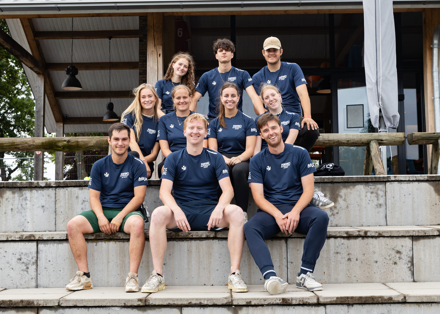Groepsfoto van ProHockey zomerkamp trainers bij hockeyclub Prinsenbeek, gekleed in marineblauwe teamkleding.
